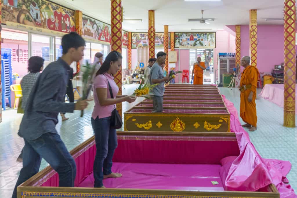 Die ersten Gläubigen besteigen den mit rosa Stoff ausgeschlagenen Zeremoniensarg