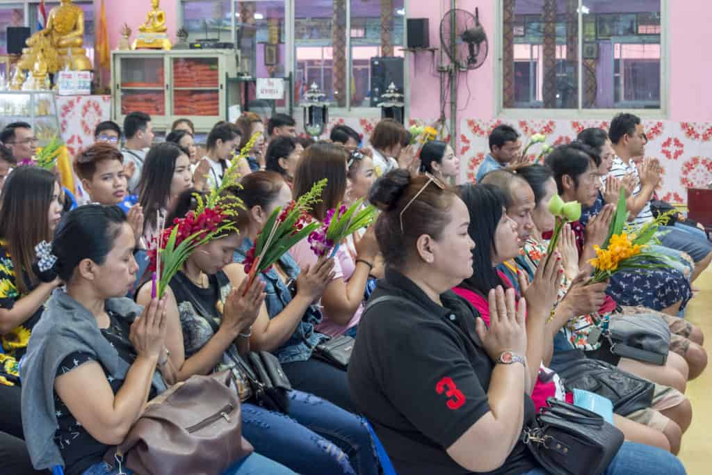 Betende Buddhisten mit Blumen in den Händen im Wat Ta Kien