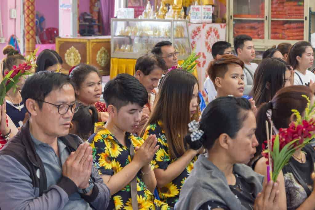 Betende Buddhisten mit Blumen in den Händen