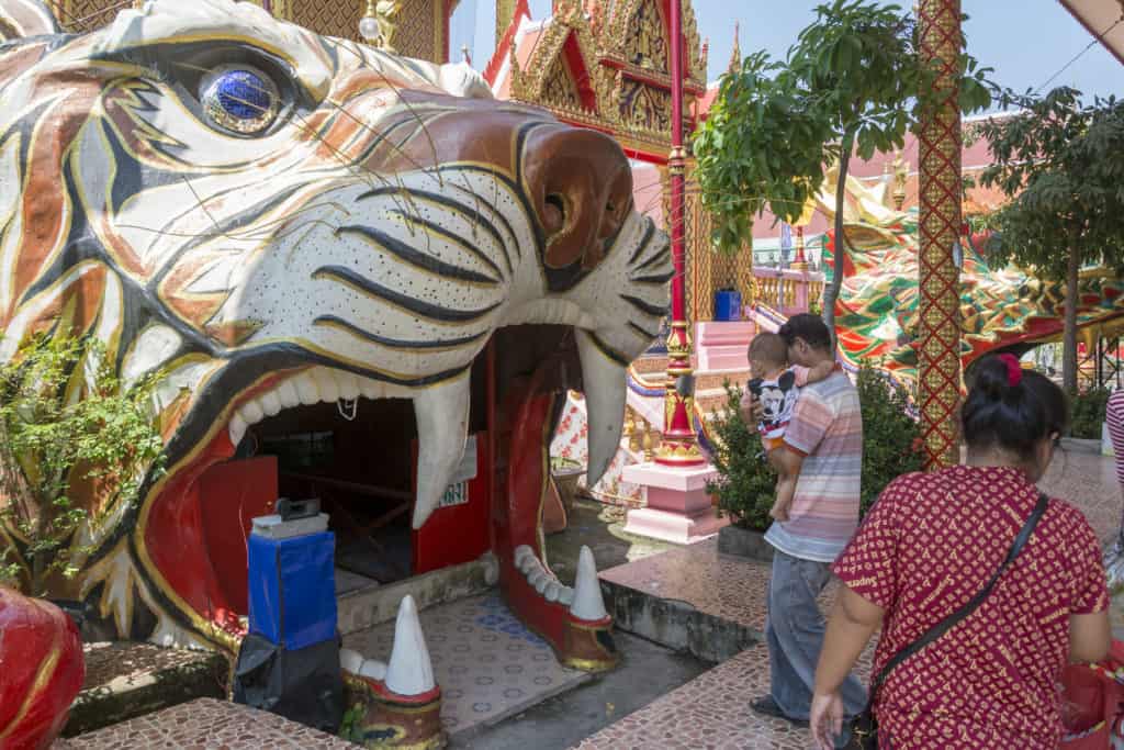 Familie betritt durch den Tigerkopf das Kellergewölbe im Wat Ta Kien