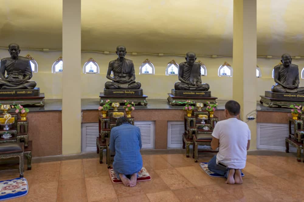 Gläubige beten kniend vor Buddha Figur