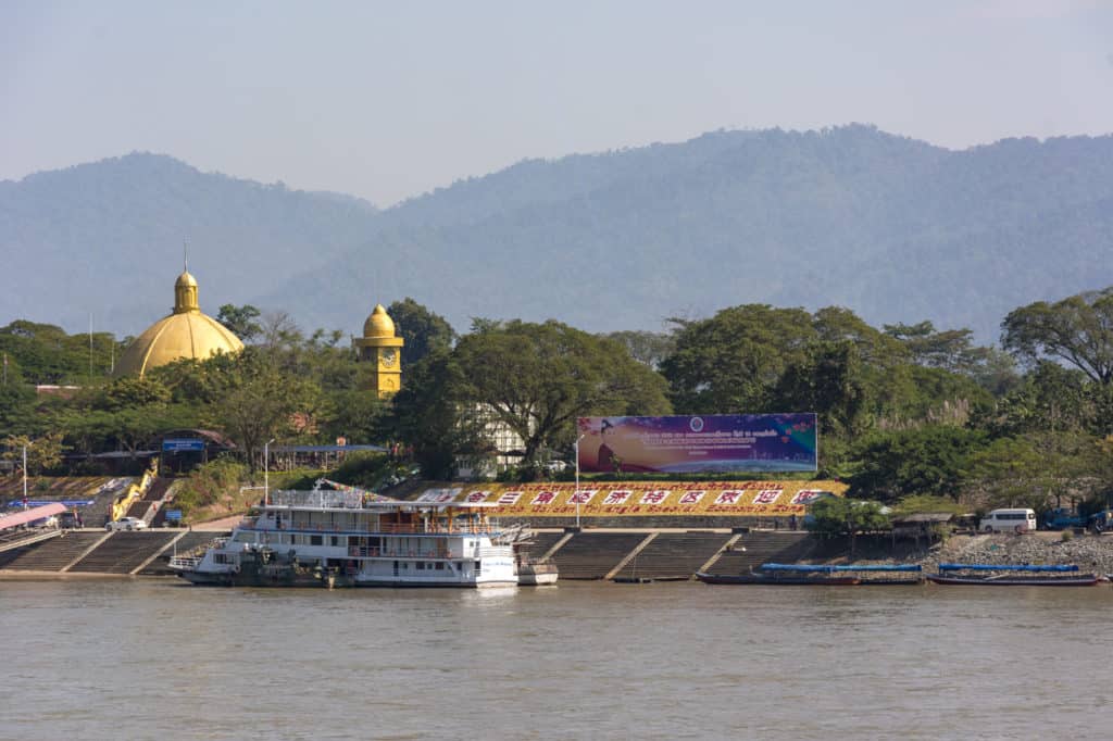 Tribüne am Ufer des Mekongs in Laos mit Uhrenturm und Tempelkuppel