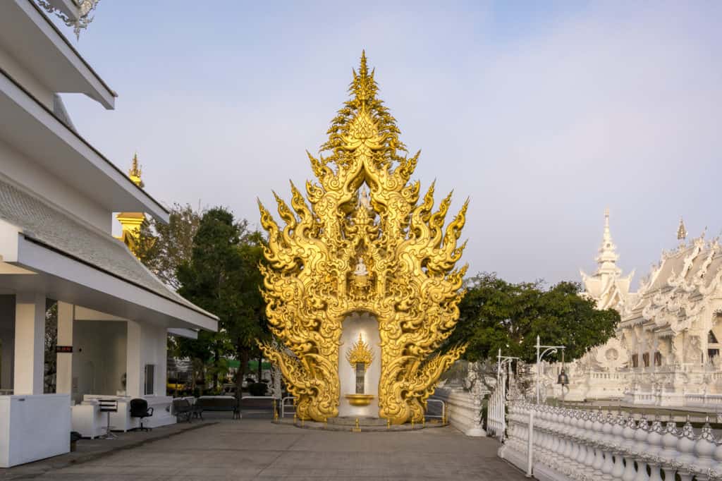  Ganz in Gold gehalten wirkt der Buddha Relics Tower vor dem blauen Himmel im Weißen Tempel beeindruckend.