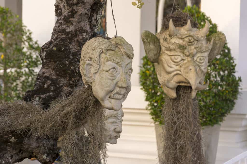 Steinmasken an einem Baum als Sinnbild der vielen Verstorbenen Seelen im Weißen Tempel von Chiang Rai