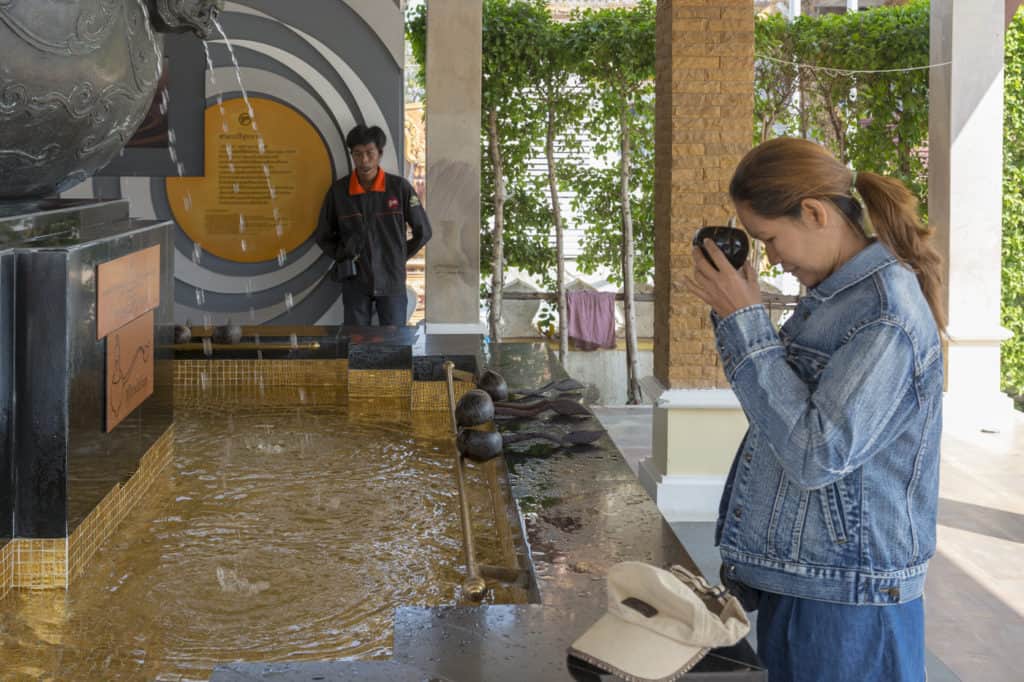 Thailänderin betet mit dem heiligen Wasser vor der Stirn