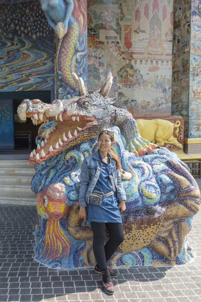 Thailänderin vor einem imposantem Drachen als Größenvergleich im Wat Ban Rai in Thailand