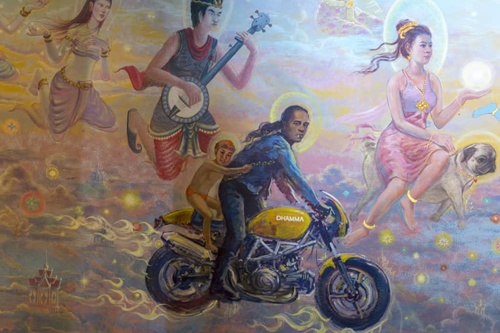 Wandgemälde im Tempel Wat Ban Rai, Motorradfahrer mit Kind, ohne Helm dafür auf einer schweren Maschine Namens Dharma.