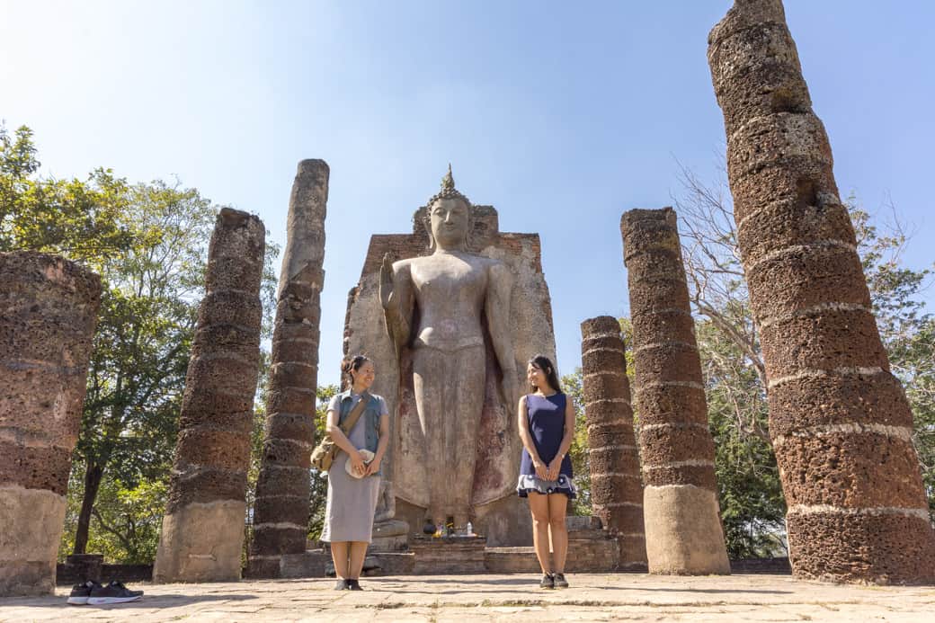 Zwei junge Thaifrauen vor dem aufrecht sthenden Bhudda im Wat SaPhan Hin
