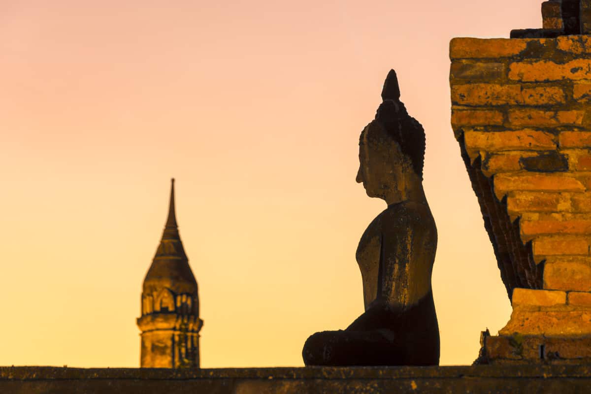 Buddha-Figur im Gegenlich beim Sonnenuntergang im Wat Mahatat im historical park Sokhothai