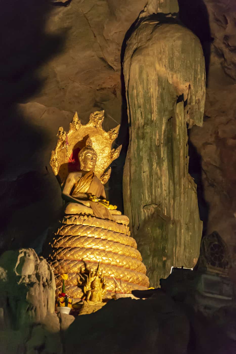 Goldener Buddha neben Stalakmiten und Stalagtiten in der Khao Luang Höhle in Phetchaburi Thailand
