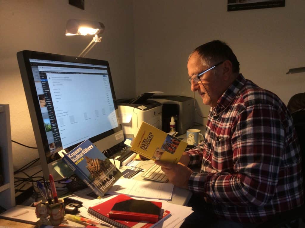 Reiner Kerner mit Buch am Computer bei der Reiseplanung