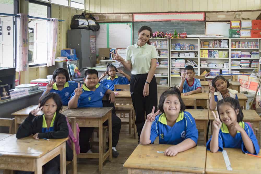 Winkende Kinder mit Lehrerin einer thailändischen Schule