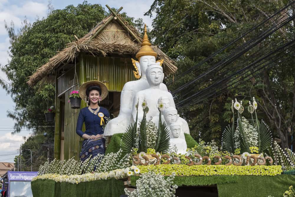 Junge Thailänderin auf dem Festwagen mit Buddha-Figuren