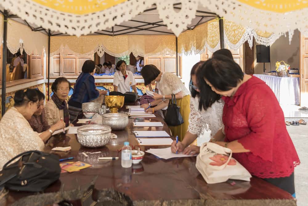 Frauen an einem Tisch sammeln Geld ein als Geschenk für den Tempel
