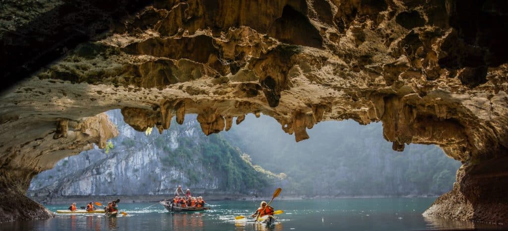 Paddelboote mit Touristen in einer Karsthöhle in der Halog Bucht Vietnam