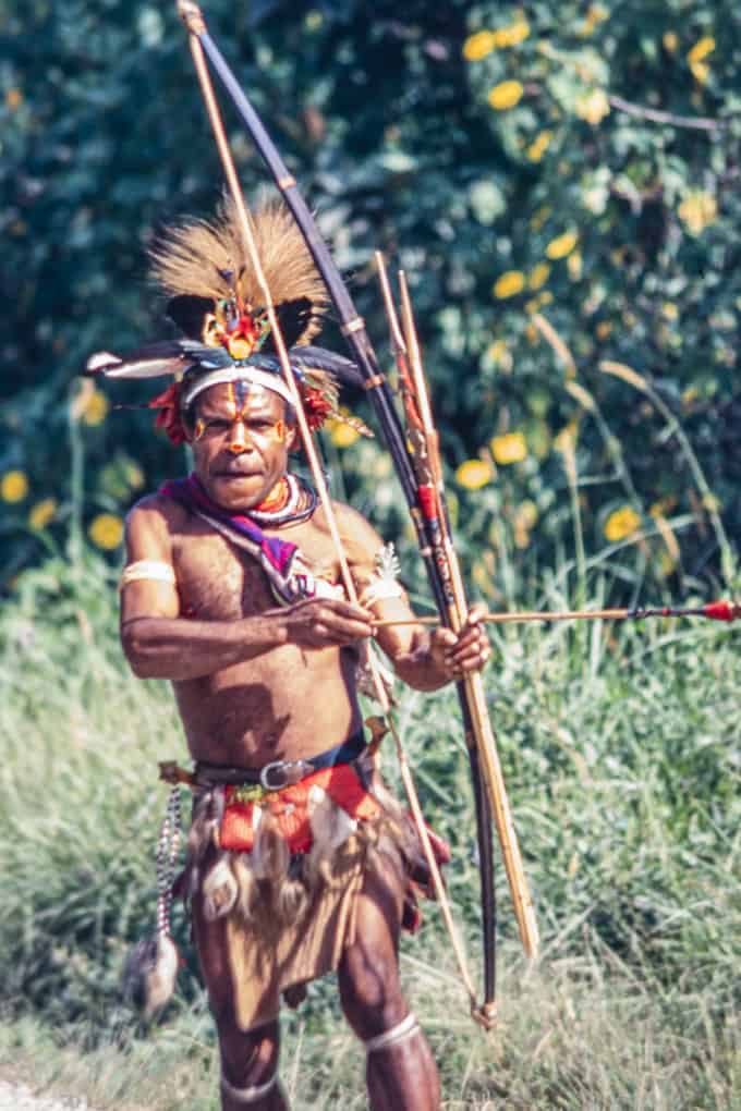 Der Krieger in Papua-Neuguinea bietet Pfeil und Bogen zum Kauf an