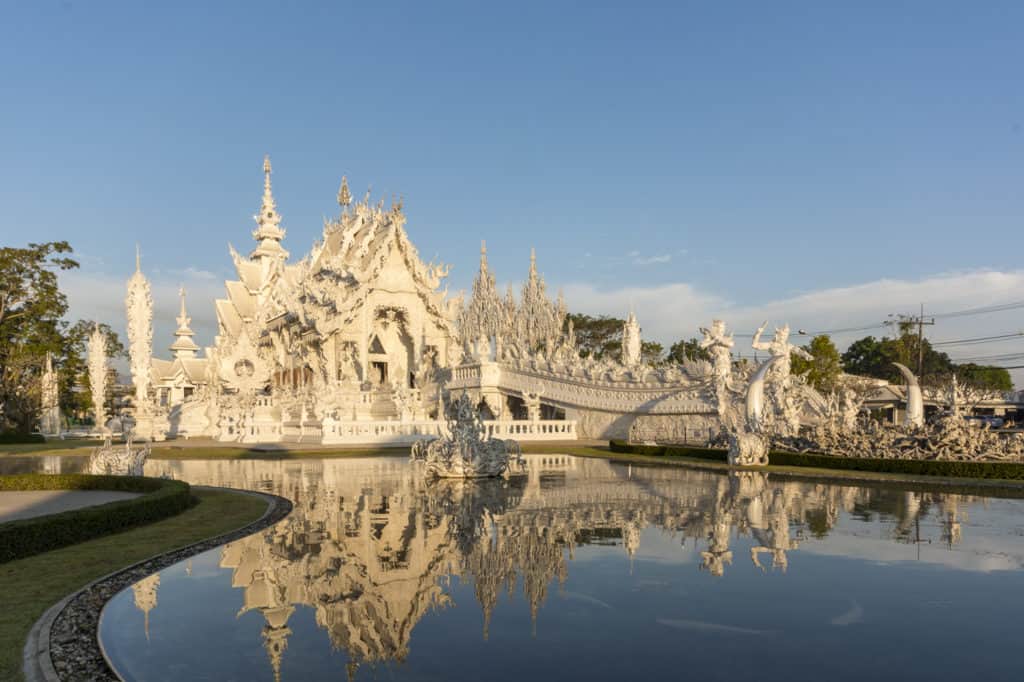 Der Weiße Tempel in Chiang Rai im Morgenlich spiegelt sich im Wasser - Wat Rong Khun