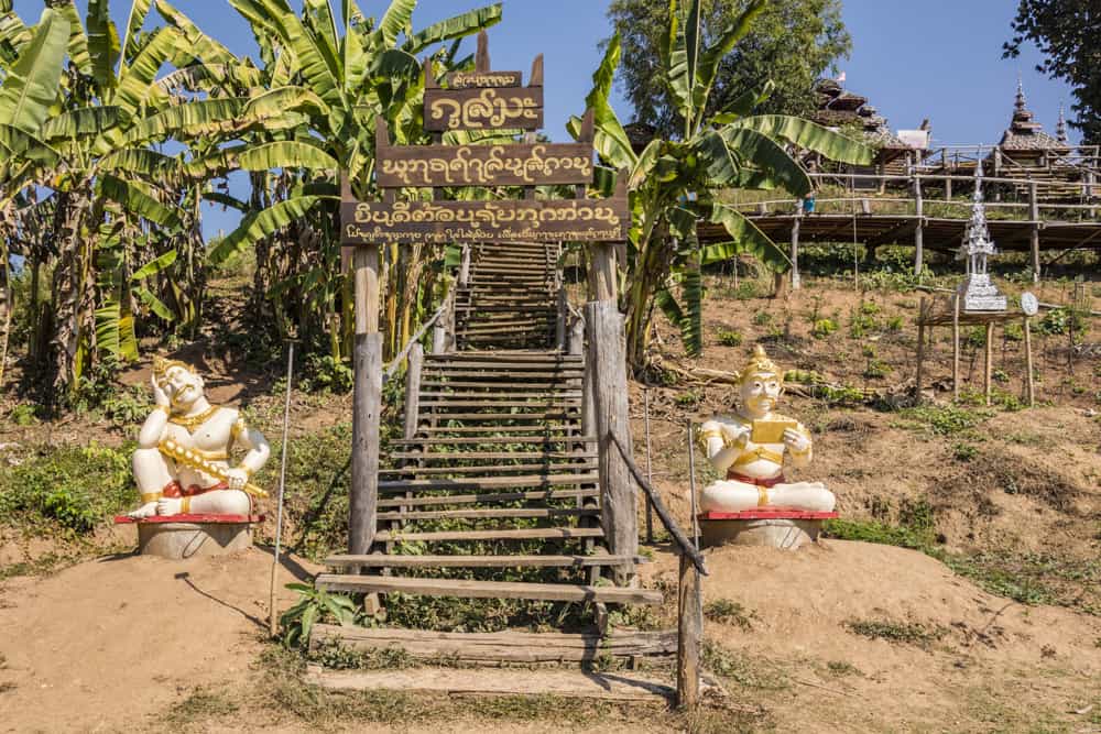 Zwei sitzende Betonfiguren am Aufgang zu Tempel und am Ende der Bambus-Brücke
