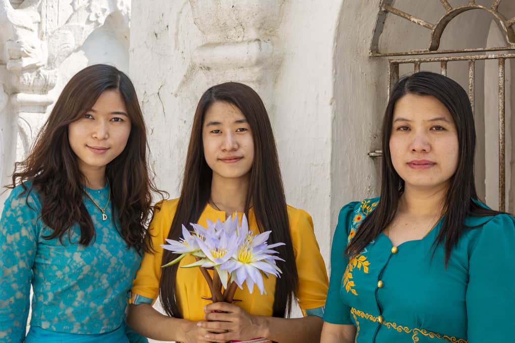 Drei junge Damen aus Myanmar legen Lotos-Blüten zu Ehren Buddhas ab